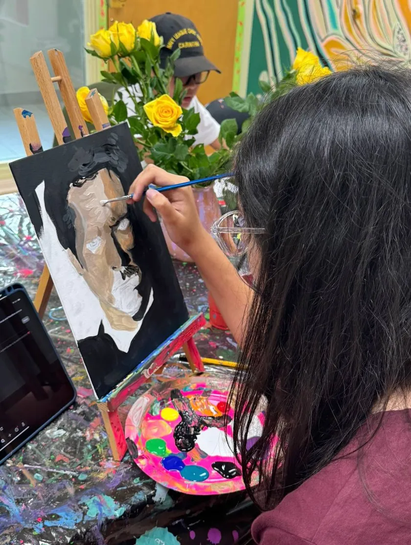Teen painting an acrylic portrait on canvas in class
