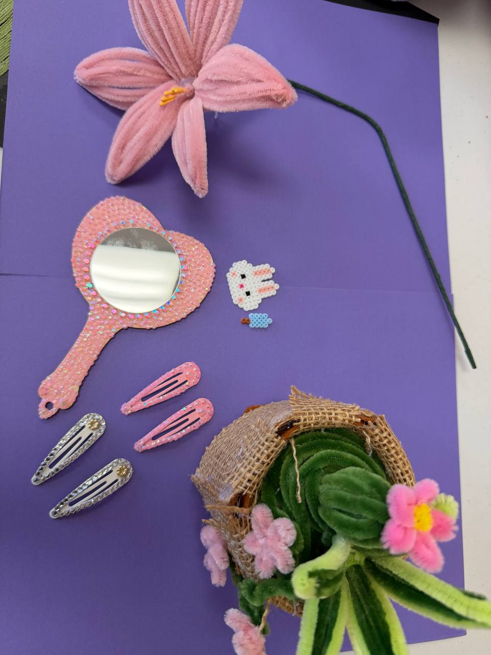 Finished camper projects: a pipe cleaner flower, a beaded mirror, decorated hair clips and a succulent pot